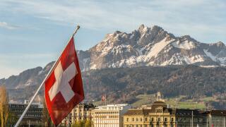 Swiss National Flag in Lucerne in Central Switzerland with the mountain range of Mt Pilatus in the background