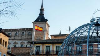 Toledo, Spain - December 23, 2024: A Spanish flag flies atop Alcazar from Zocodover square during christmas time