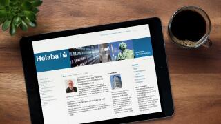 The website of Helaba is seen on an iPad tablet, on a wooden table along with an espresso coffee and a house plant (Editorial use only).