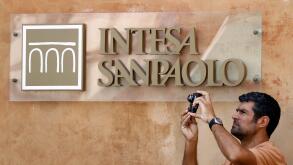 A man takes a picture in front of Intesa Sanpaolo bank in downtown Rome July 23, 2010. The European Union is examining whether some banks need to raise capital as it looks to dispel concerns about weakness in the sector and repair an interbank lending mar