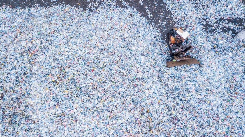 Aerial top view large garbage bottle pile background, Garbage pile in trash dump, Waste from household, Bottle waste disposal in dumping site, excavator machine is working on a mountain garbage.