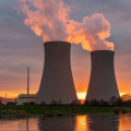 Nuclear power plant smoke stacks set against the dawn sky next to a river