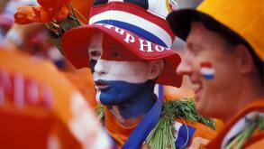 The Netherlands. Amsterdam. Supporters of Dutch football team in national colours. Flag (red, white, blue) and national colour (orange).
