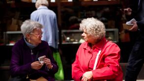 Two old age female pensioners sitting on a seat chatting about their pension money in Dundee, UK