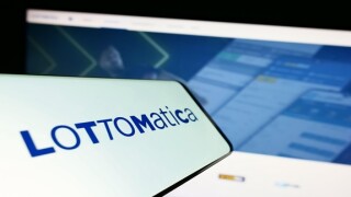 Cellphone with logo of Italian gambling company Lottomatica S.p.A. on screen in front of website. Focus on center-right of phone display.