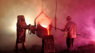 Pouring molten iron in a steel mill reenactment, metallurgical workers with ladle bucket, hot, smoky, and dangerous, Bethlehem, Pennsylvania, USA.