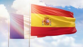 Sunny blue sky and flags of spain and france