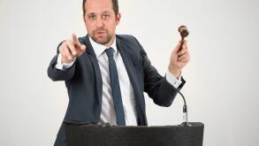 A male auctioneer in action holing a gavel during a live auction.