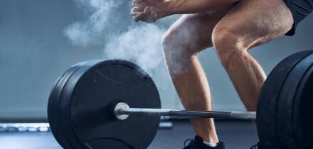 Close-up of man clapping hands before barbell workout at gym