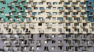 The facade of a multi-apartment new residential building with balconies and windows, painted in 3 colors.