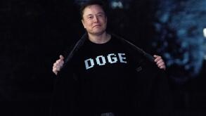 Elon Musk flashes his t-shirt that reads "DOGE" to the media as he walks on South Lawn of the White House, in Washington, Sunday, March 9, 2025. (AP Photo/Jose Luis Magana)