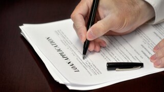 Business man signing loan application with black pen on desk