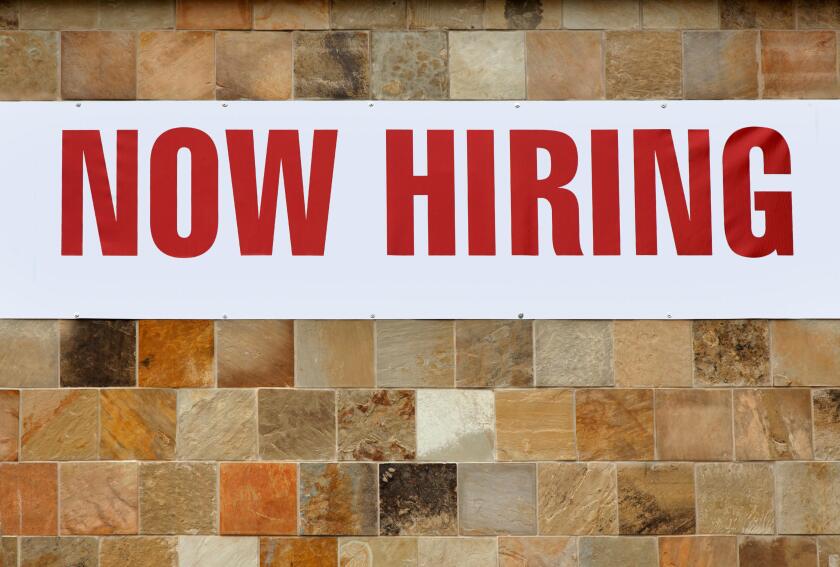 NOW HIRING sign on tiled wall.
