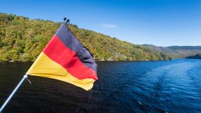 German flag on a boat on Lake Rursee with blue sky and sunlight in summer.