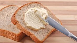 A knife spreading butter on wheat bread