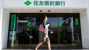 A woman walks past a branch of Sumitomo Trust and Banking Co in Tokyo November 6, 2009. Sumitomo Trust and Banking Co and Chuo Mitsui Trust Holdings Inc said they plan to merge, creating Japan's largest trust bank with scale to better compete in a crowded
