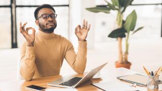 Black man meditating in office coping with stress