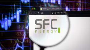 SFC Energy company logo on a website with blurry stock market developments in the background, seen on a computer screen through a magnifying glass