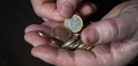 Old male hand holding euro coins, close up. Hands hold euro coins of different denominations. Inflation, purchasing power and social crisis