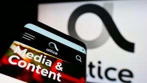 Smartphone with website of telecommunications company Altice Europe N.V. on screen in front of business logo. Focus on top-left of phone display.