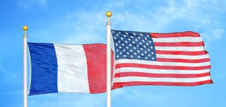 France and United States two flags on flagpoles and blue cloudy sky