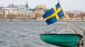 The Swedish flag flies above a ship moored on the shore in central Stockholm