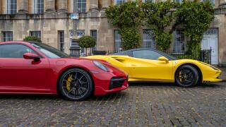 A bright yellow Ferrari and a red Porsche on a cobbled English street