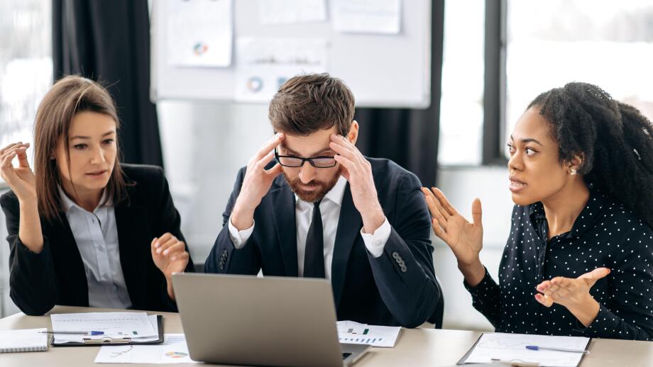 Annoyed business employees of different nationalities, work at the workplace in modern office, argue over work issues, cannot agree, experience stress from working together. Quarrel in the work team