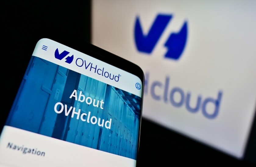 Mobile phone with webpage of French cloud computing company OVH Groupe SAS on screen in front of business logo. Focus on top-left of phone display.