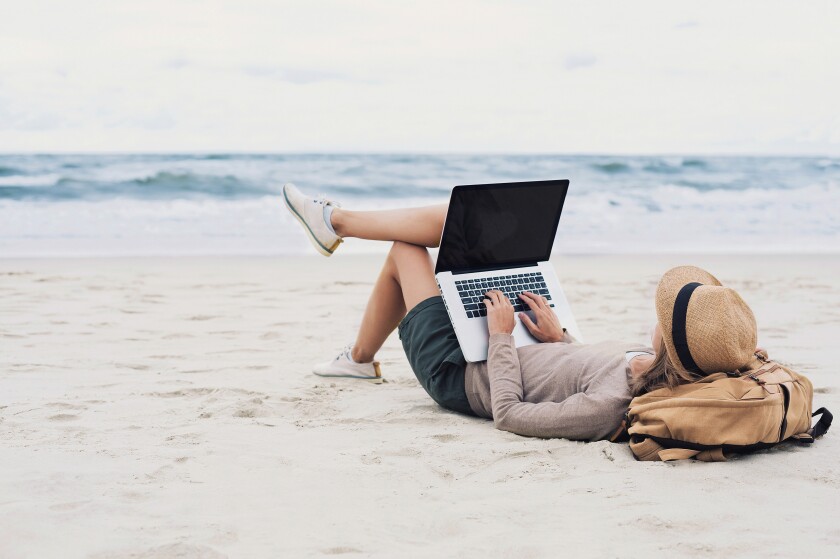 Young woman using laptop computer on a beach. Freelance work, on