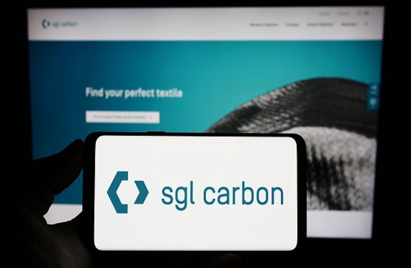 Person holding smartphone with logo of German chemicals company SGL Carbon SE on screen in front of website. Focus on phone display.
