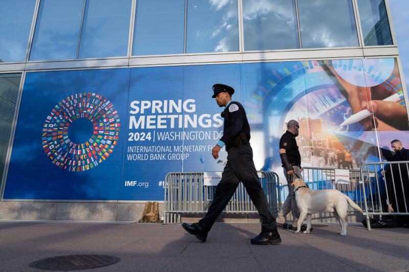 An International Monetary Fund police officer walks by an IMF banner, during the World Bank/IMF Spring Meetings in Washington, Thursday, April 18, 2024. (AP Photo/Jose Luis Magana)