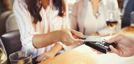 Woman paying bartender with credit card contactless payment at bar