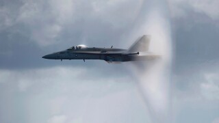 A US Navy F/A-18C Hornet breaks the sound barrier while flying over the aircraft carrier USS Carl Vinson.