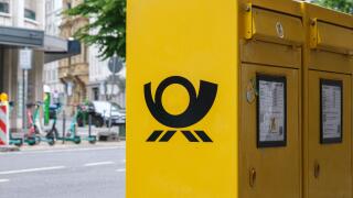 German yellow post box with Deutsche Post logo on city street