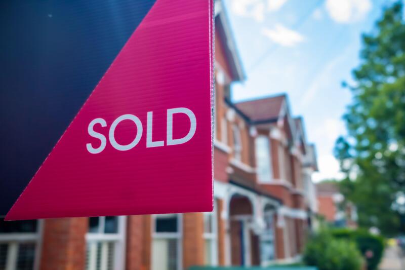 Estate agent 'SOLD' sign on residential street