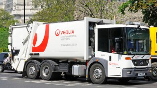 Veolia environmental services hgv tipper truck dustcart rubbish collection commercial vehicle driving along London street in Tower Hamlets England UK