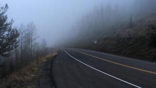 An empty mountain road during a dark, misty, evening.
