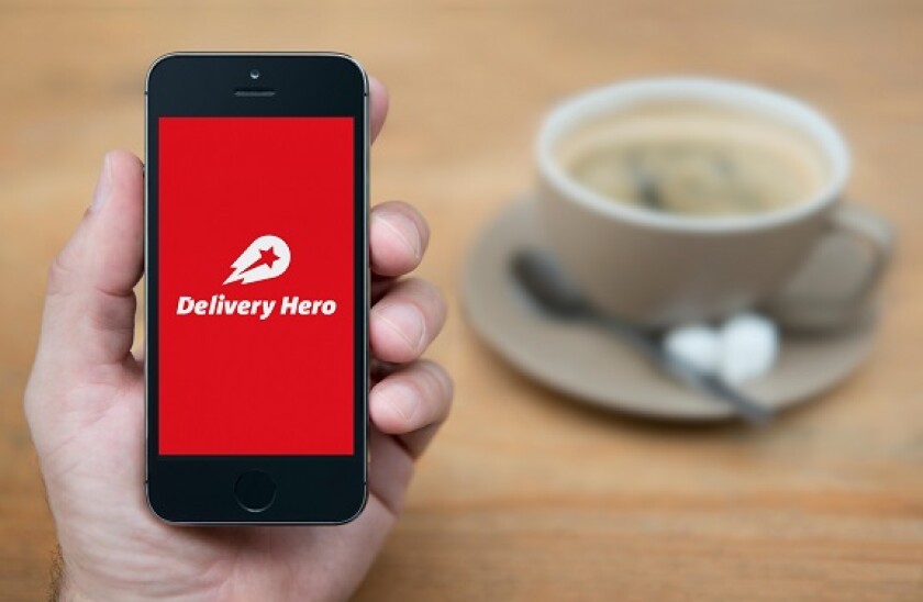 A man looks at his iPhone which displays the Delivery Hero logo (Editorial use only).