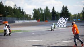 Man holding and waving the checkered flag at the finish of the race