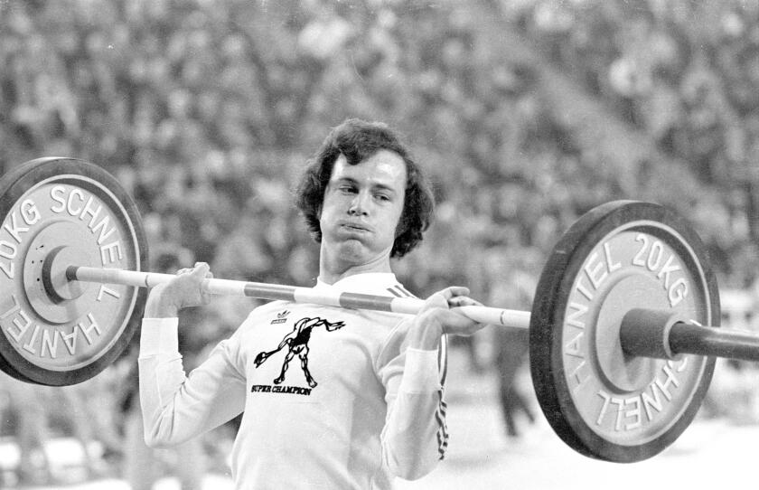 Footballer Franz Beckenbauer dabbles in weightlifting at the Sportpressefest in the Munich Olympiahalle.