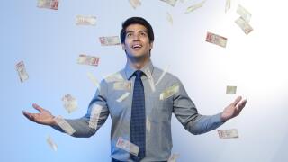 Money falling on a businessman standing with his arms outstretched
