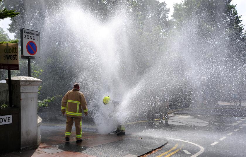 Brighton UK 26 July 2013 - Firefighters have to plug a water main after it was accidentally burst by a a vehicle which went over their hose while they were fighting a fire in Preston Drove Brighton today