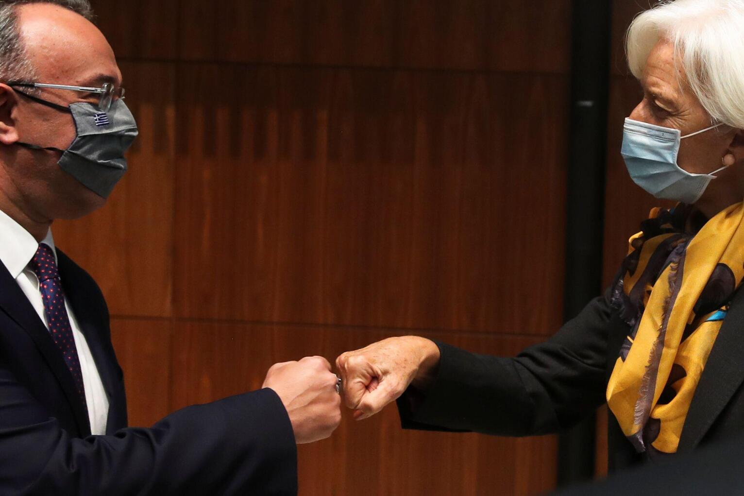 President of the European Central Bank Christine Lagarde bumps fists with Greek Finance Minister Christos Staikouras as they attend a Euro zone finance ministers meeting in Luxembourg, October 4, 2021. REUTERS/Yves Herman