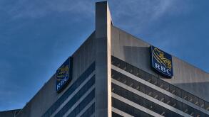 Low angle view of tall skyscraper with offices in Vancouver downtown with logo of Royal Bank of Canada (RBC) on top and blue sky.