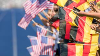 Spectators waving with flags of Germany and USA in front of a blue tartan track. Focus is on the german flags in the foreground
