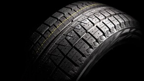 Modern winter car tyre. Horizontal composition. Low key.