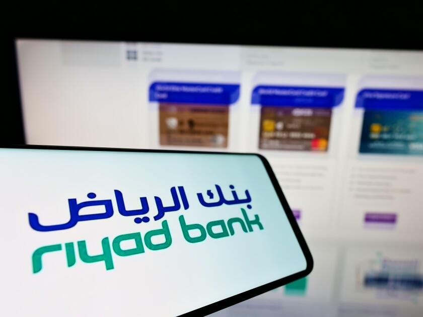 Cellphone with logo of Saudi Arabian financial company Riyad Bank SJSC on screen in front of business website. Focus on center of phone display.