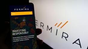 Person holding cellphone with website of British investment company Permira Holdings Limited on screen with logo. Focus on center of phone display.