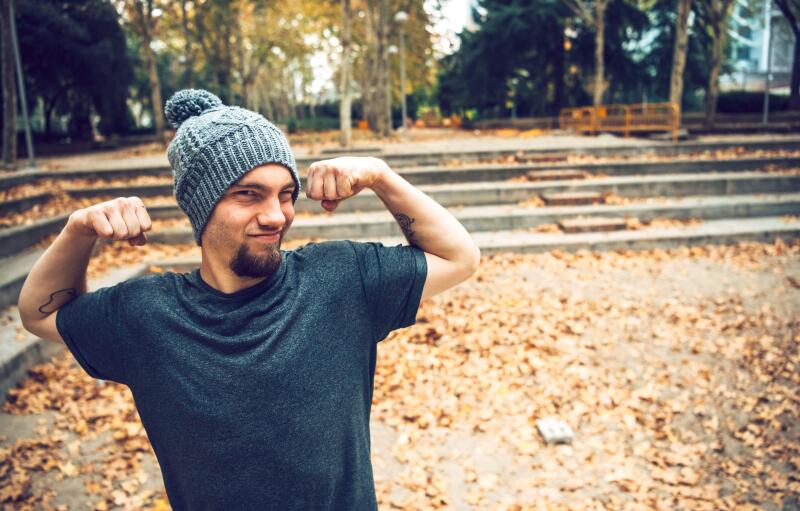 Man flexing muscles while standing in park during autumn